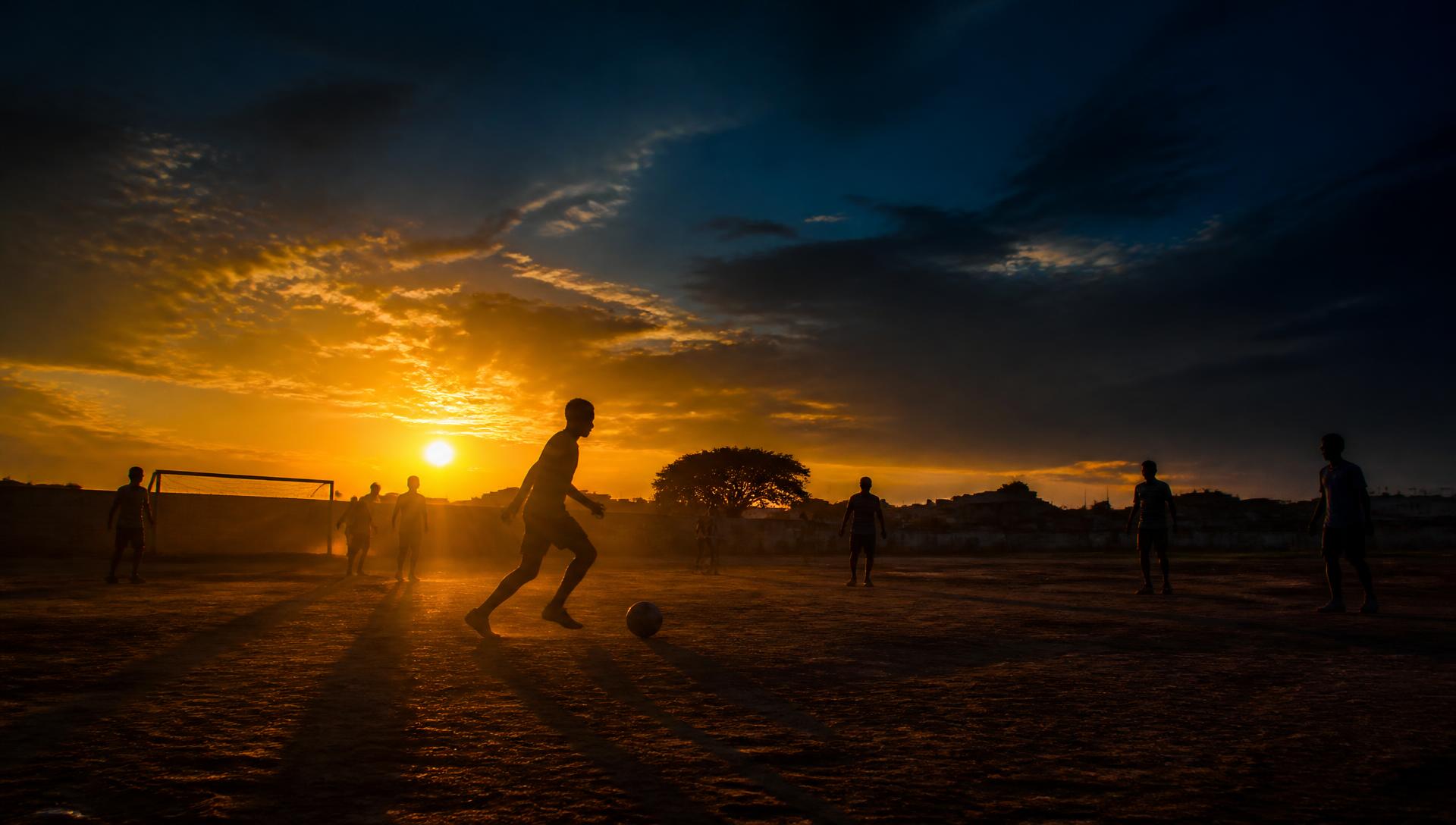 Jogo de futebol comunitário ao pôr do sol no Kilamba